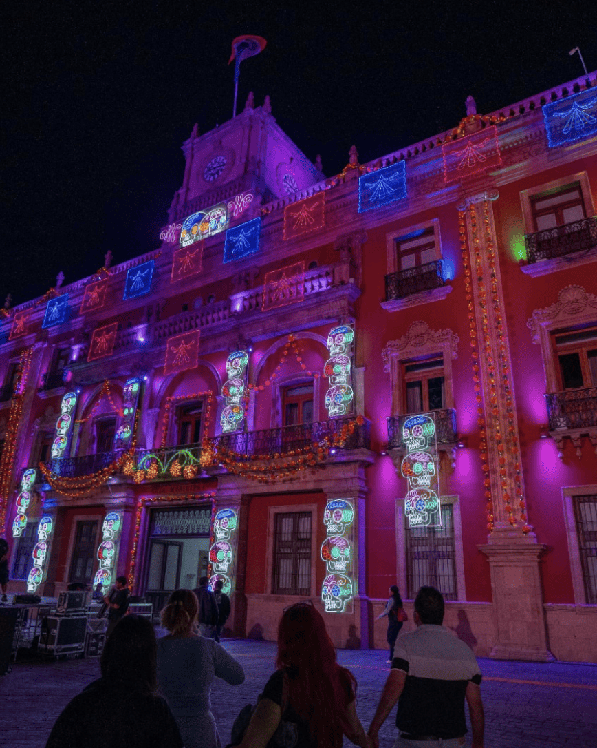Facade of the Palacio de León illuminated with colored lights during the 2026 Day of the Dead Festival.