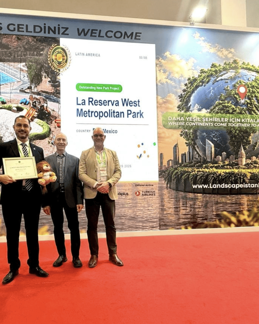 Cuatro personas en evento de premiación en León, Guanajuato, con pantalla que muestra parques y reconocimiento internacional.